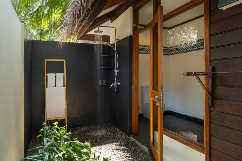 Douche extérieure avec sol en galets et paroi ajourée.