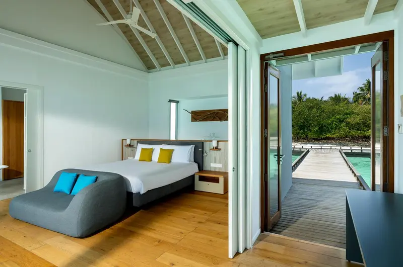 Une chambre lumineuse s'ouvre sur une terrasse en bois avec vue sur la mer.