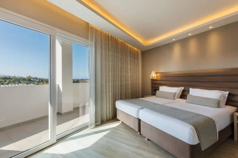Chambre lumineuse avec deux lits simples et balcon.