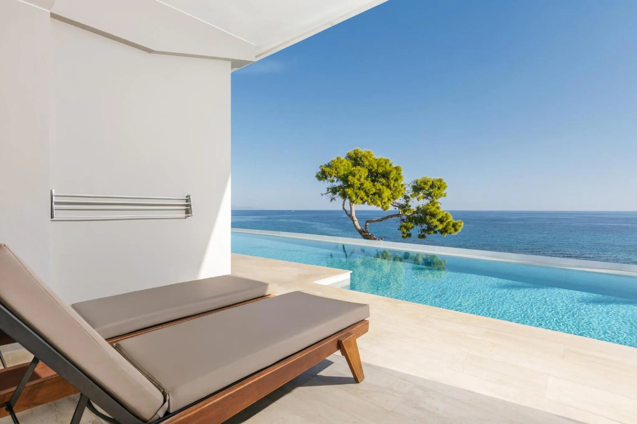 Deux transats invitent à la détente face à une piscine à débordement et une vue sur la mer.