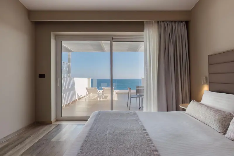 Une chambre lumineuse s'ouvre sur une terrasse avec vue sur la mer.