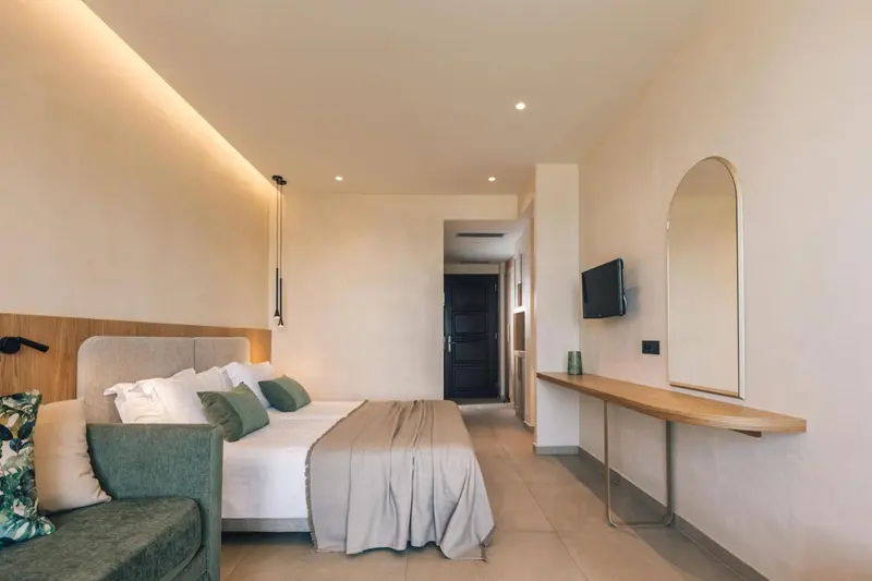 Chambre lumineuse avec un grand lit et un miroir mural.