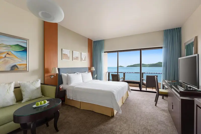 Chambre lumineuse avec un grand lit donnant sur la mer.