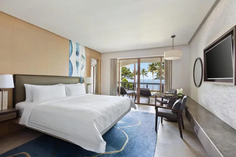 Chambre lumineuse avec un grand lit et vue sur la mer.