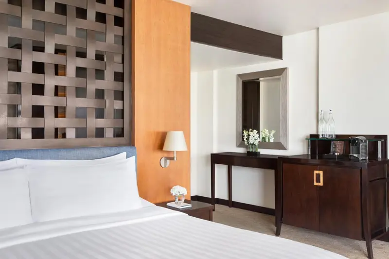 Une chambre lumineuse avec un lit blanc et un mobilier en bois sombre.