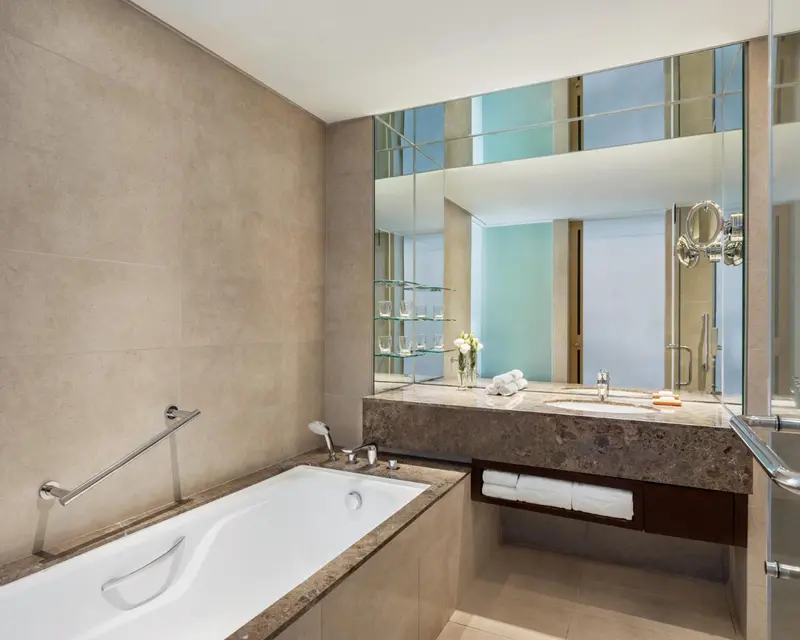 Une baignoire blanche est encastrée dans une salle de bain carrelée.