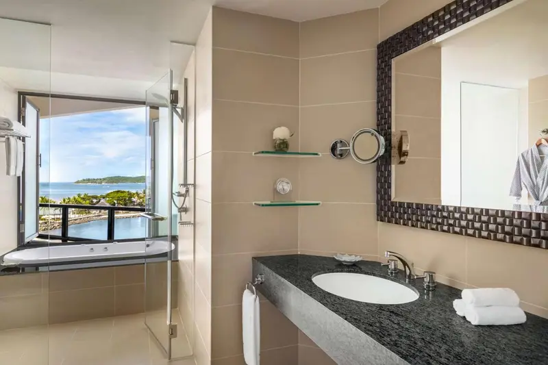 Une salle de bain lumineuse avec baignoire et vue sur la mer.