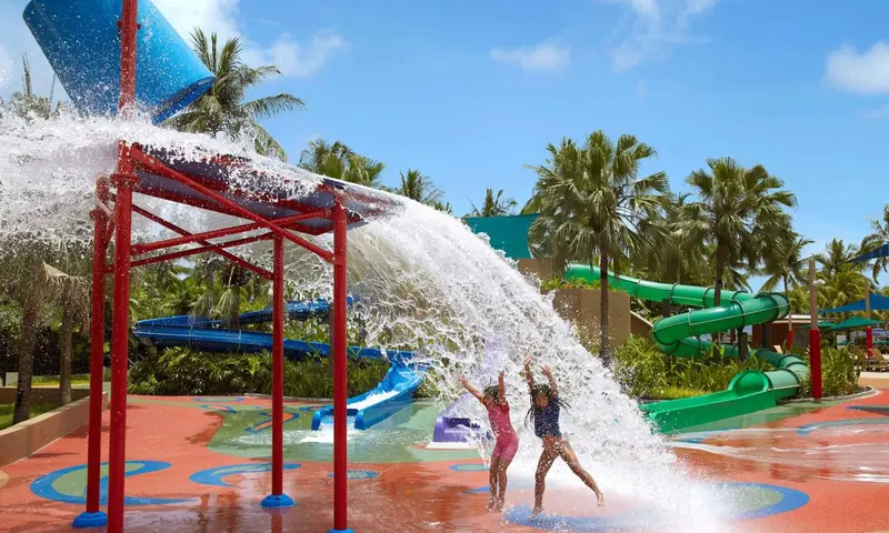 Des enfants s'amusent sous une structure d'eau dans un parc aquatique.