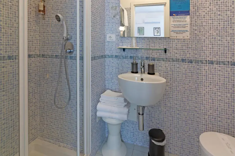 Une salle de bain claire avec douche à l'italienne et vasque.
