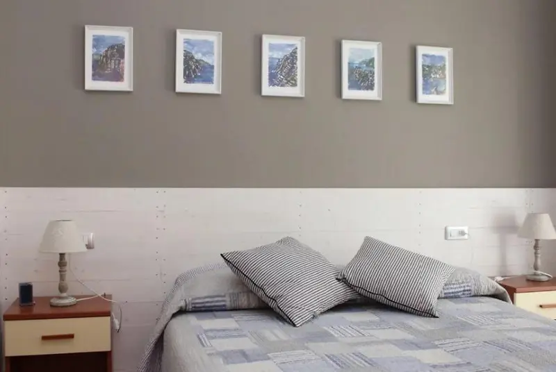 Une chambre à coucher avec un lit recouvert d'une couverture et de coussins, éclairée par deux lampes de chevet.