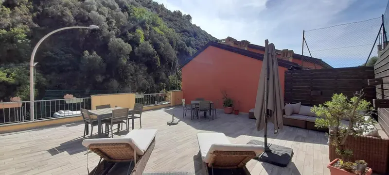 Terrasse aménagée avec mobilier de jardin et vue sur la végétation.