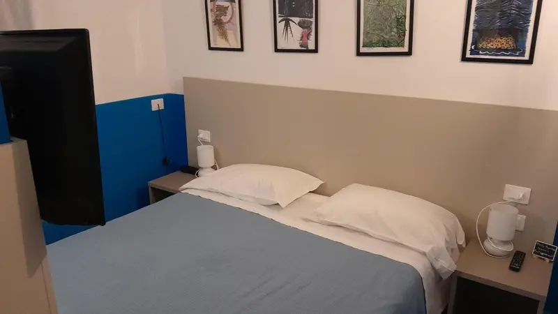 Une chambre avec un grand lit et une télévision murale.