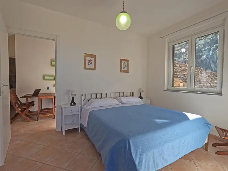 Une chambre lumineuse avec un lit double et un coin lecture.