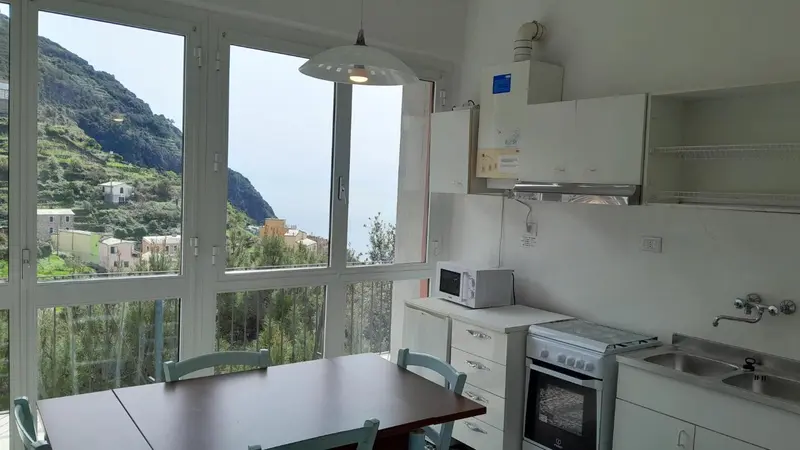 Une cuisine lumineuse s'ouvre sur une vue dégagée sur la montagne et la mer.
