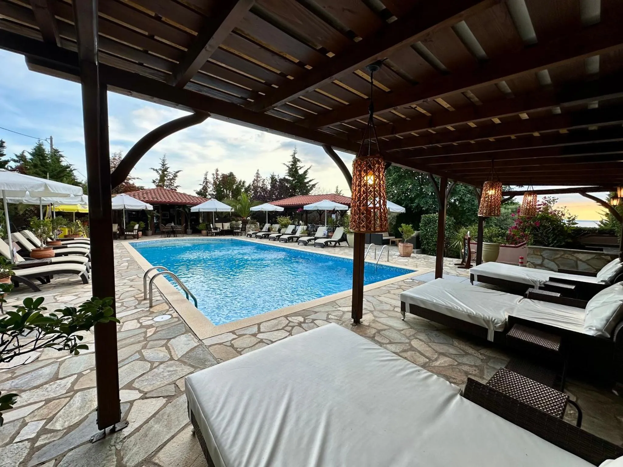 Terrasse ombragée donnant sur une piscine et des transats.