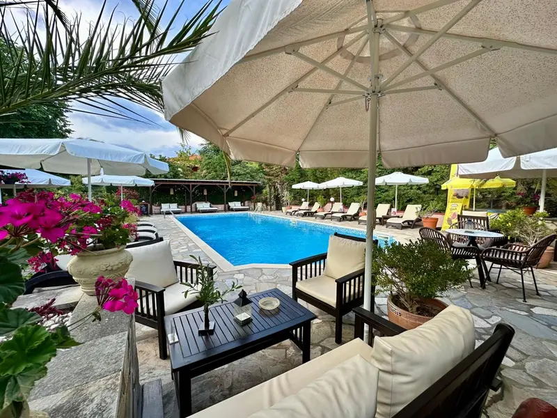 Espace de détente avec mobilier blanc et parasols au bord d'une piscine.