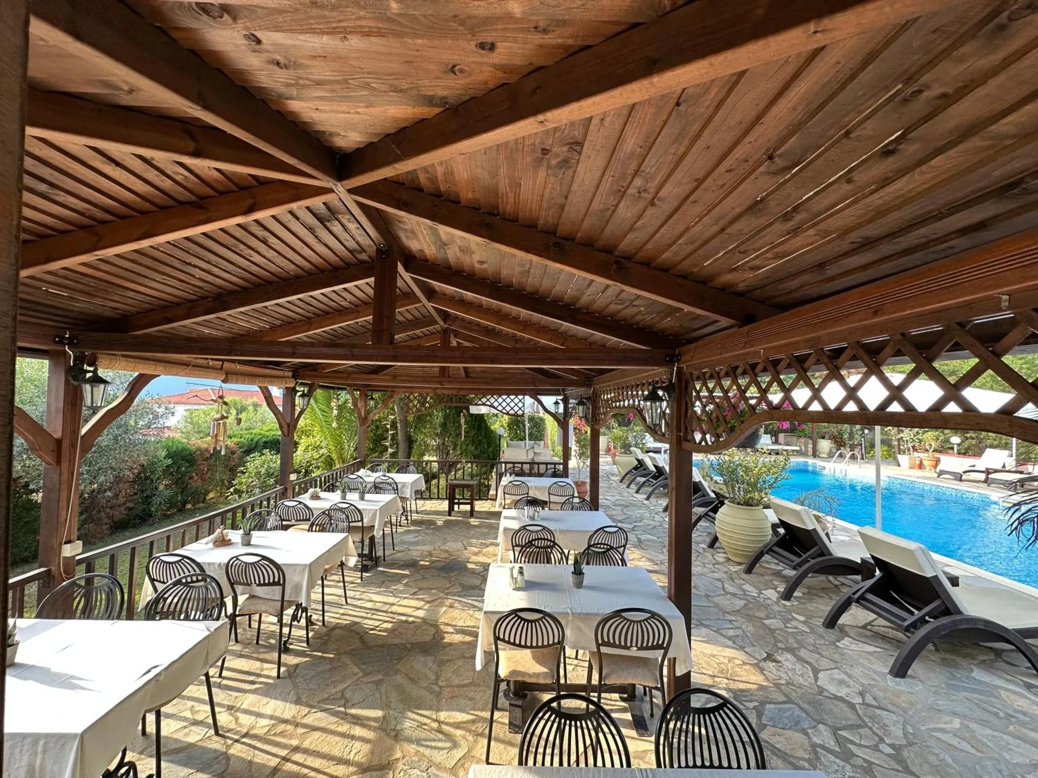 Une terrasse ombragée abrite des tables et des chaises pour les repas.