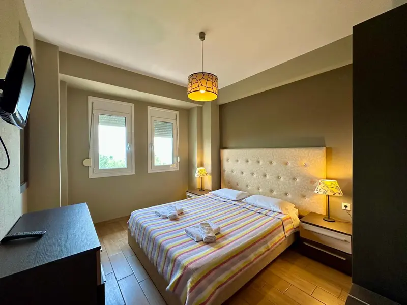 Une chambre lumineuse avec un grand lit et deux fenêtres.