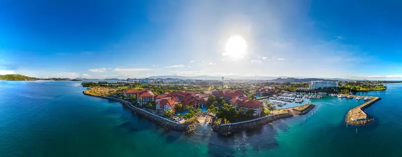 Vue aérienne d'un complexe hôtelier bordant une baie turquoise ensoleillée.
