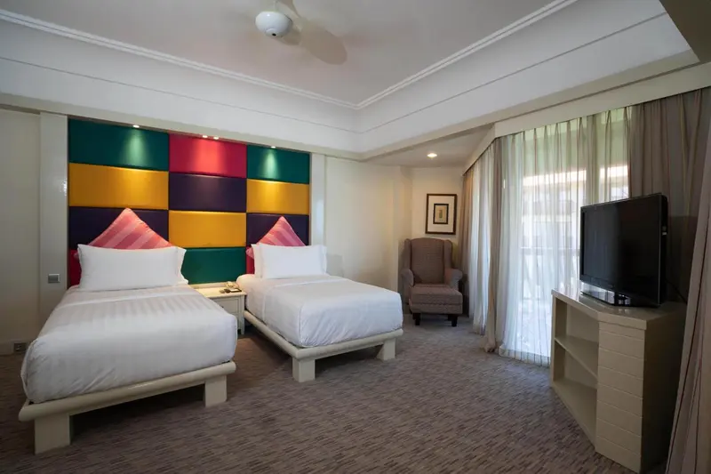 Chambre lumineuse avec deux lits simples et un coin salon.