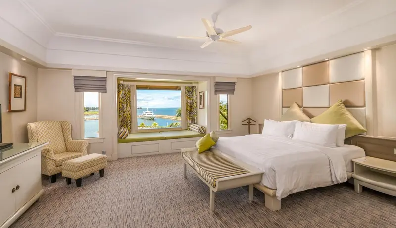 Chambre lumineuse avec un grand lit et une vue sur la mer.