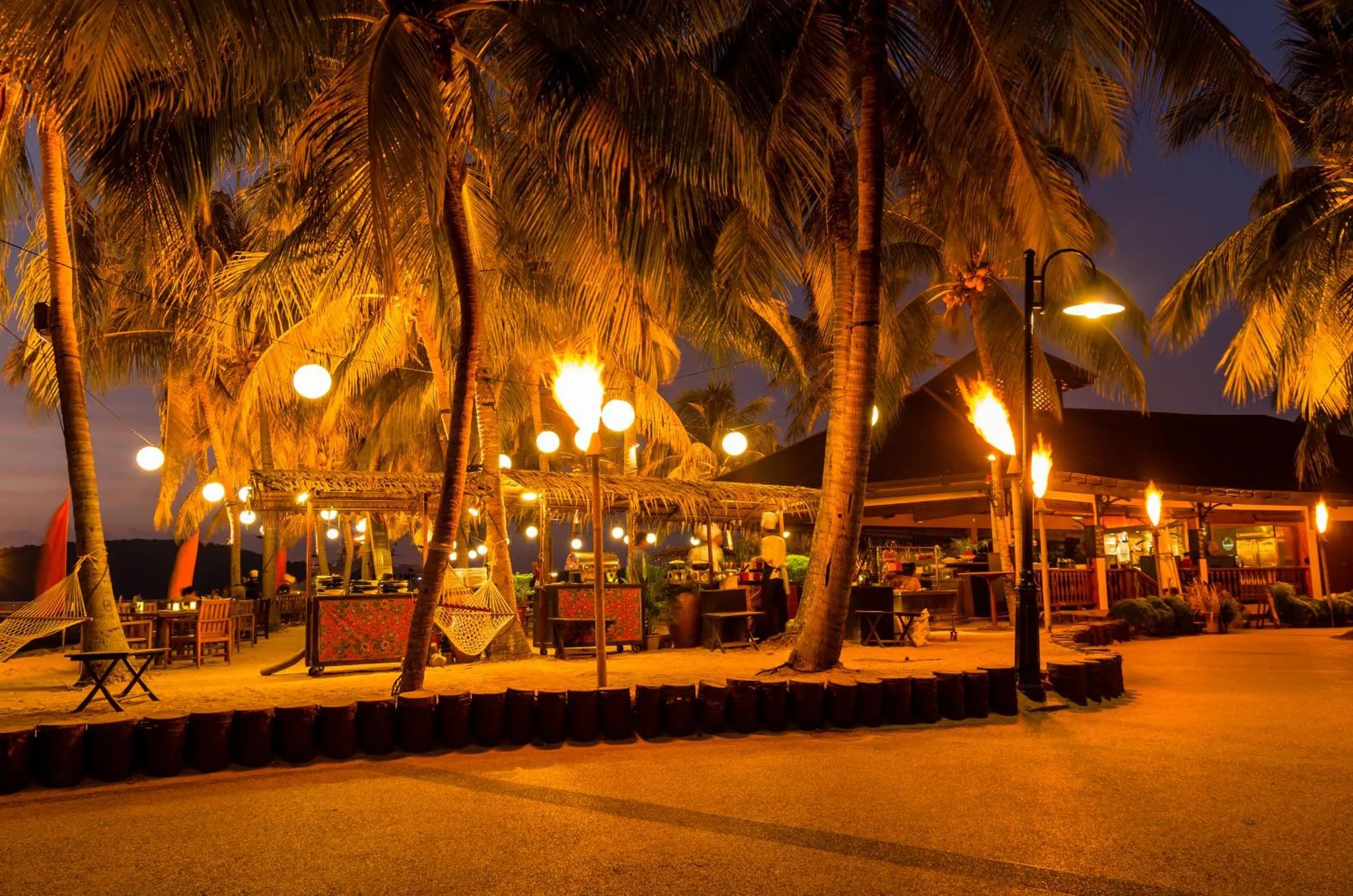 Eclairage chaleureux sur une terrasse de restaurant en bord de mer au crépuscule.