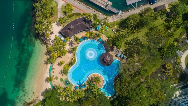 Vue aérienne d'un complexe hôtelier avec piscine et plage.