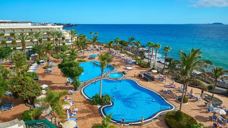 Vue aérienne d'un complexe hôtelier avec piscines et accès à la mer.