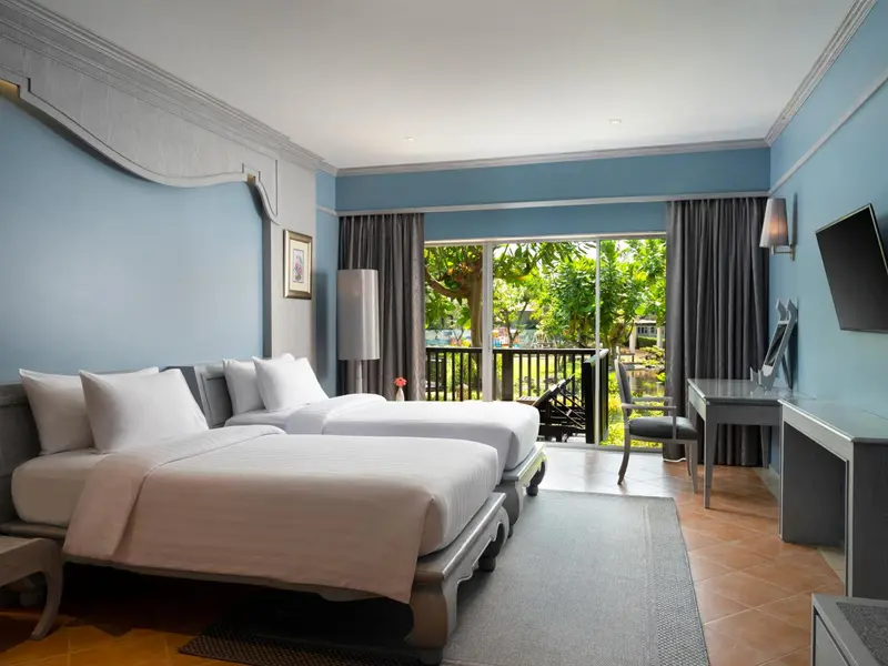 Une chambre lumineuse avec deux lits simples et un accès à une terrasse.