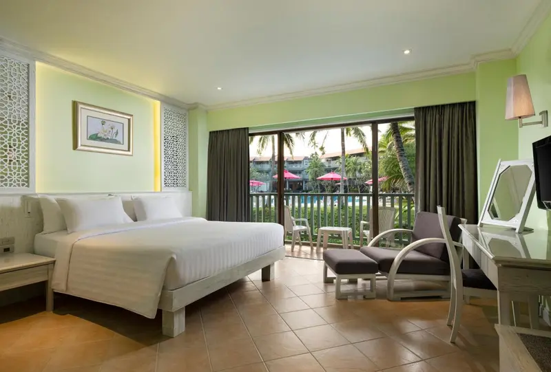Chambre lumineuse avec un grand lit et vue sur une terrasse et une piscine.
