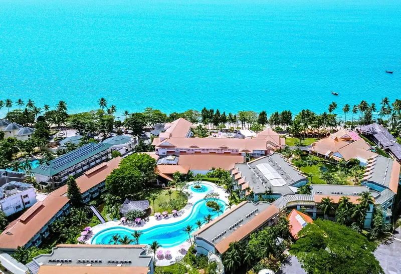 Vue aérienne d'un complexe hôtelier avec piscine et végétation luxuriante.