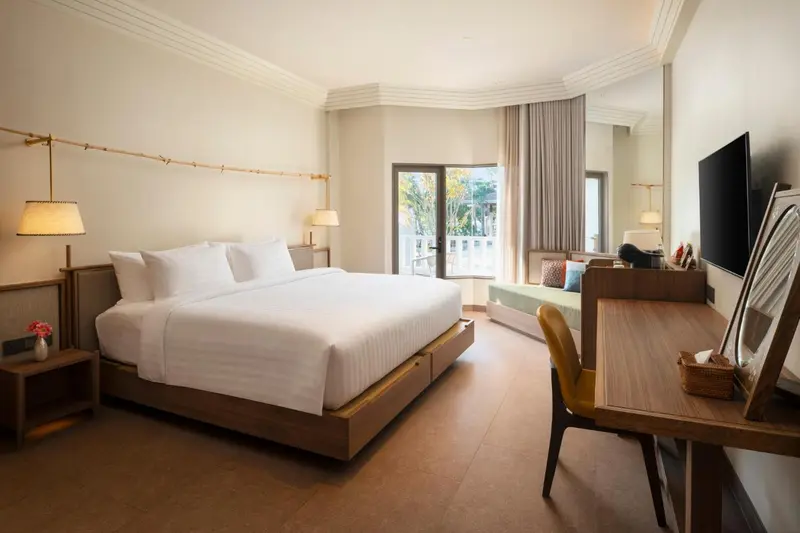 Une chambre lumineuse avec un grand lit et un espace détente près de la fenêtre.