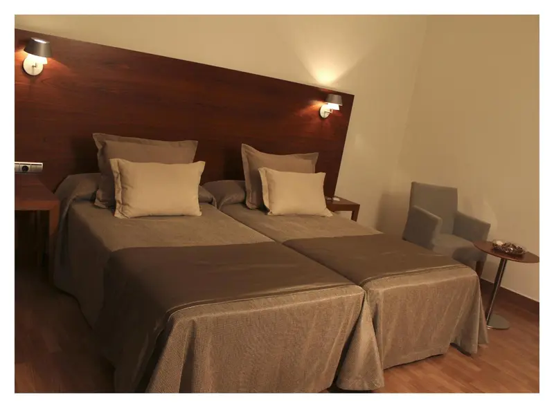 Une chambre avec deux lits simples et une assise.