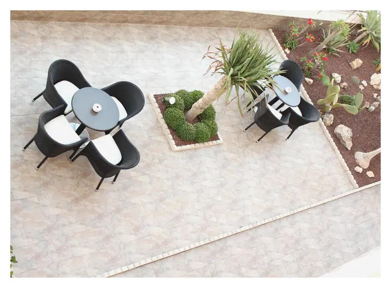 Tables et chaises noires et blanches sur une terrasse carrelée.