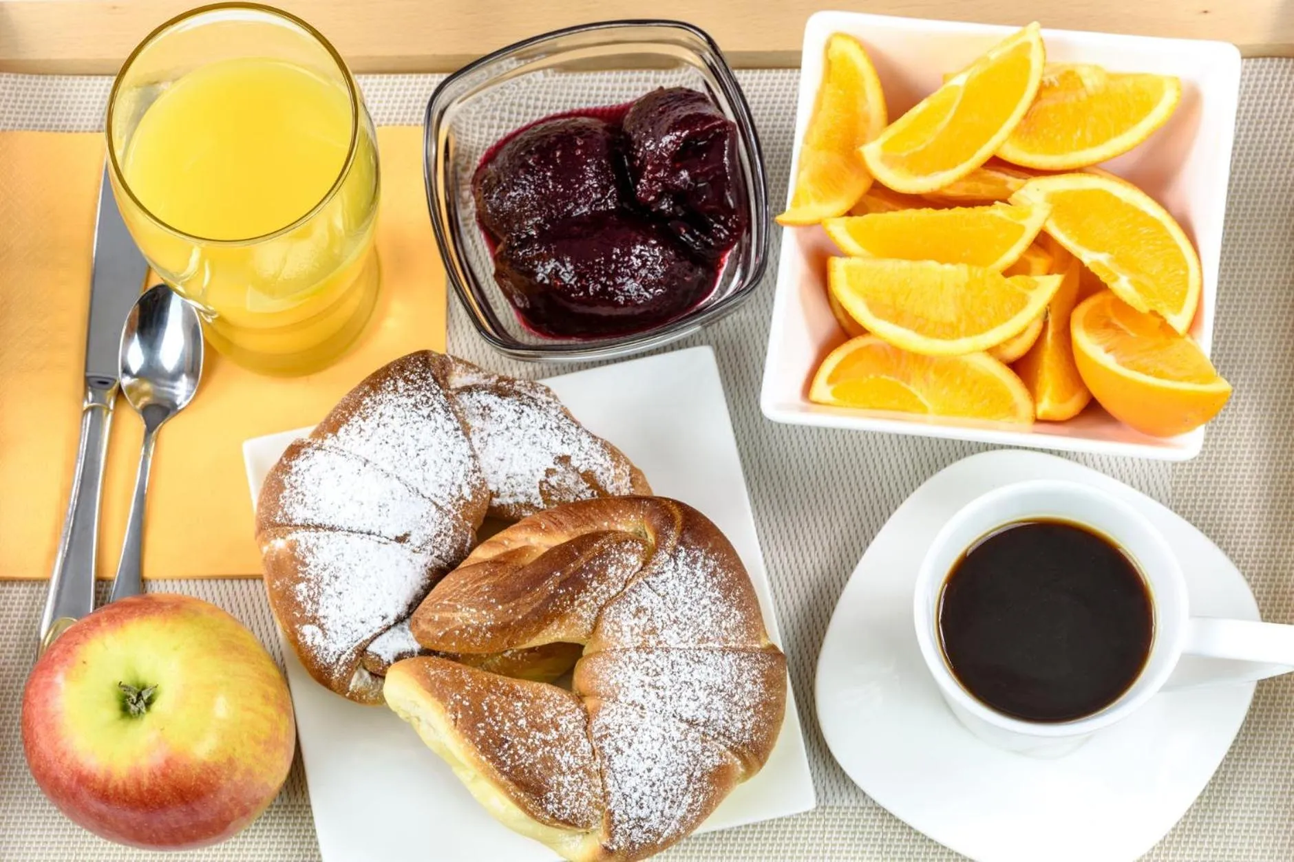 Un petit-déjeuner avec un croissant, des fruits et des boissons.