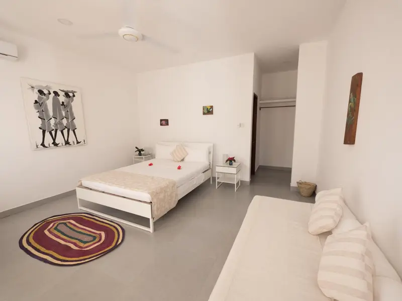 Une chambre lumineuse avec un lit recouvert d'une couverture et de fleurs.