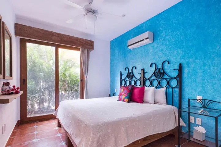 Une chambre lumineuse avec un grand lit et un mur bleu texturé.