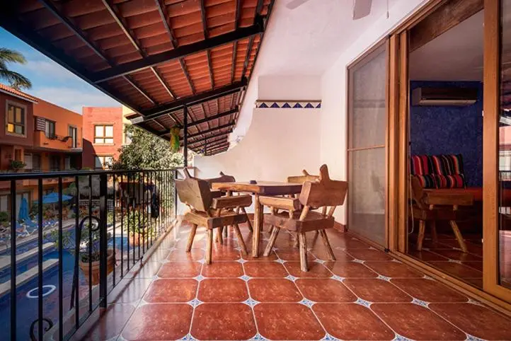 Terrasse carrelée avec mobilier en bois et vue sur une piscine.
