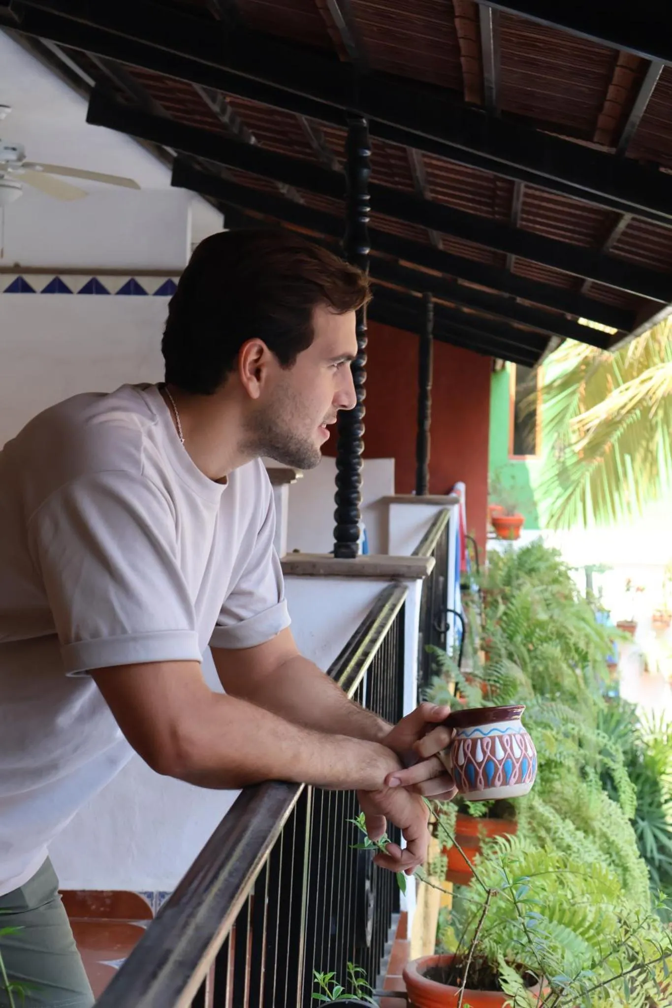 Un homme regarde au loin depuis une terrasse ombragée.