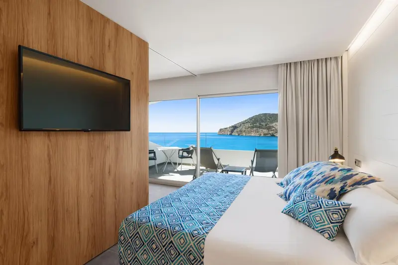 Chambre lumineuse avec un grand lit donnant sur une vue mer.