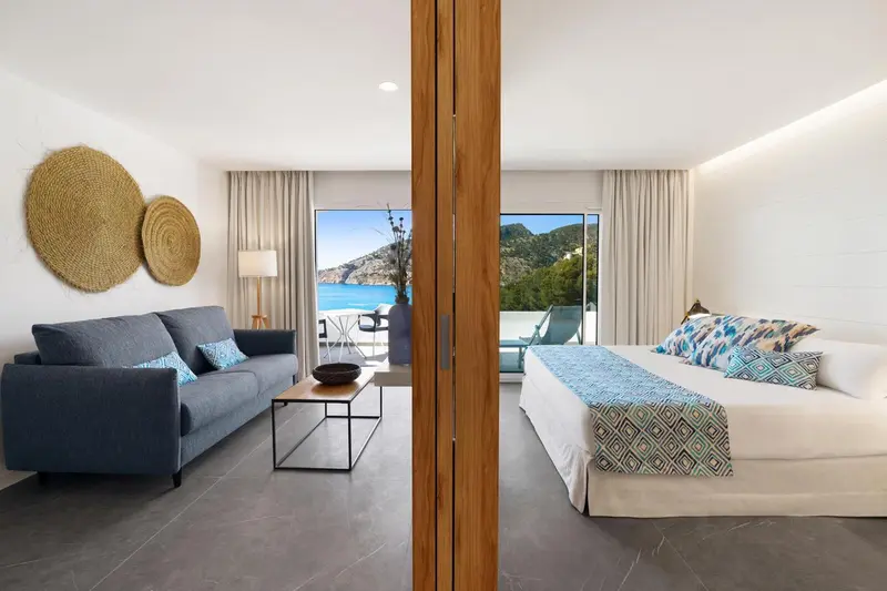 Espace de vie lumineux avec canapé et chambre à coucher donnant sur une vue mer.