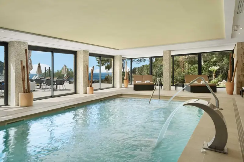 Une piscine intérieure avec un espace de détente et une vue sur la mer.