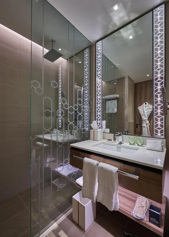 Une salle de bain moderne avec une grande douche à l'italienne et un miroir lumineux.