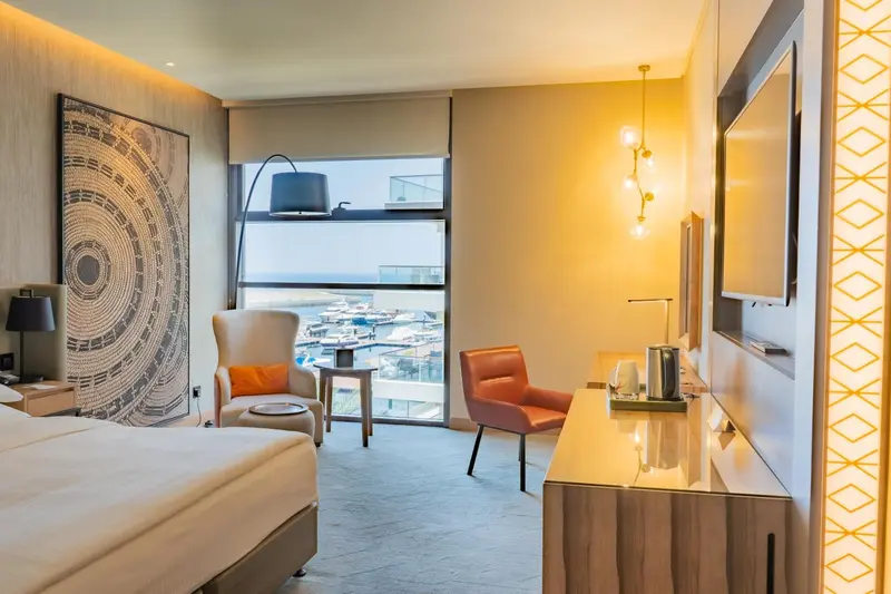 Une chambre lumineuse avec un coin lecture et une vue sur la ville.