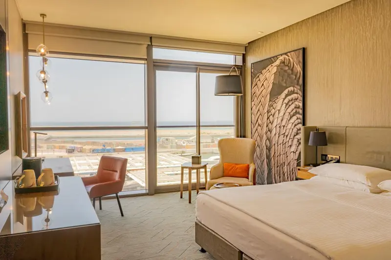 Chambre lumineuse avec un grand lit et une vue sur la mer.