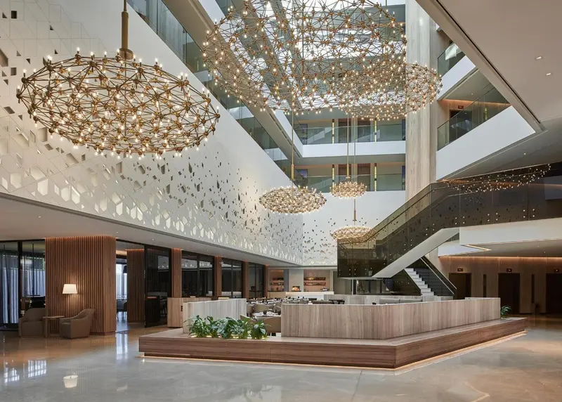 Vaste hall d'accueil avec un comptoir de réception en bois et des luminaires décoratifs.