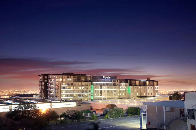 Bâtiment moderne illuminé au crépuscule avec une vue sur la ville.