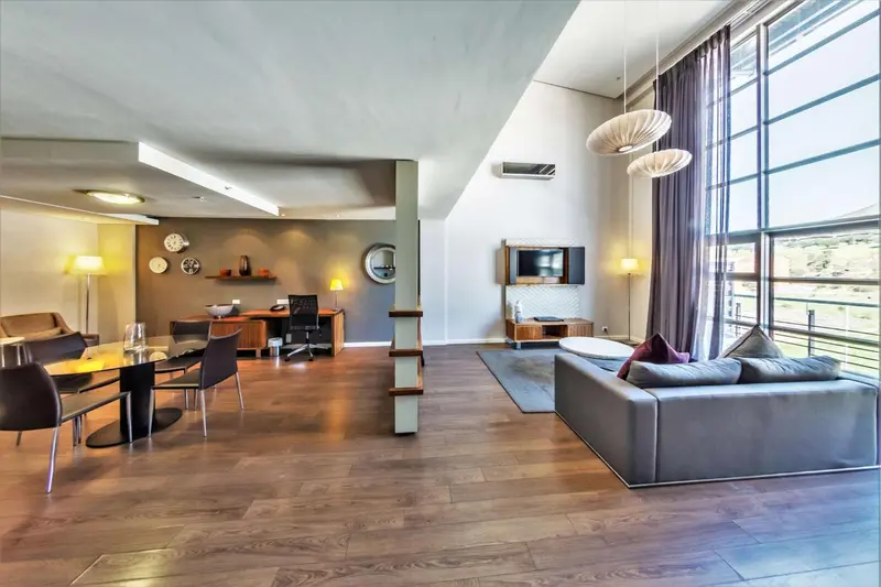Espace de vie moderne avec coin repas et canapé gris.