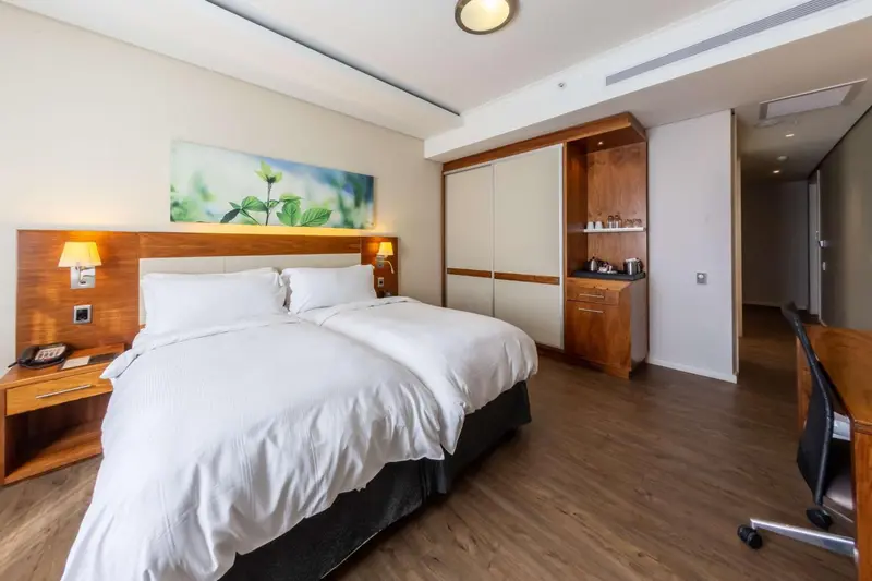 Une chambre lumineuse avec un grand lit et un bureau.