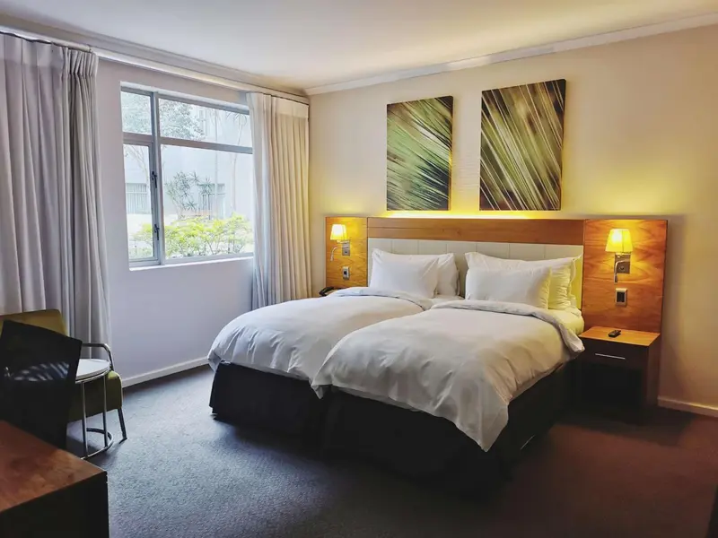 Une chambre d'hôtel lumineuse avec un grand lit et des tableaux décoratifs.